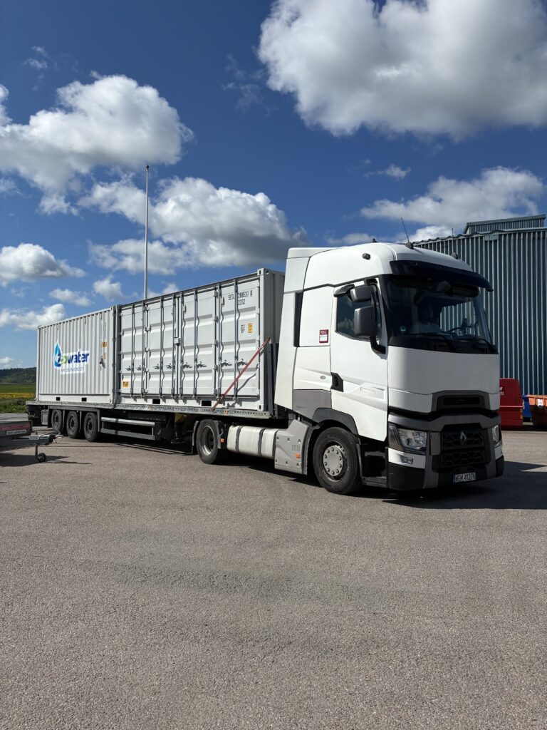 En vit lastbil transporterar en vattenreningscontainer för snabb installation och flexibel kemisk förbehandling på plats.